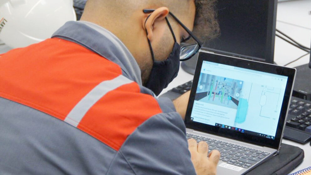 A chemical technician trainee sits in front of the e-learning material, already seeing the virtual twin from the VR experience