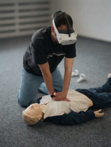 Teilnehmer trainiert die Herzdruckmassage an einer Übungspuppe mit VR-Brille.